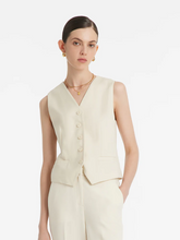 a lady in a beige single-breasted vest with white pants